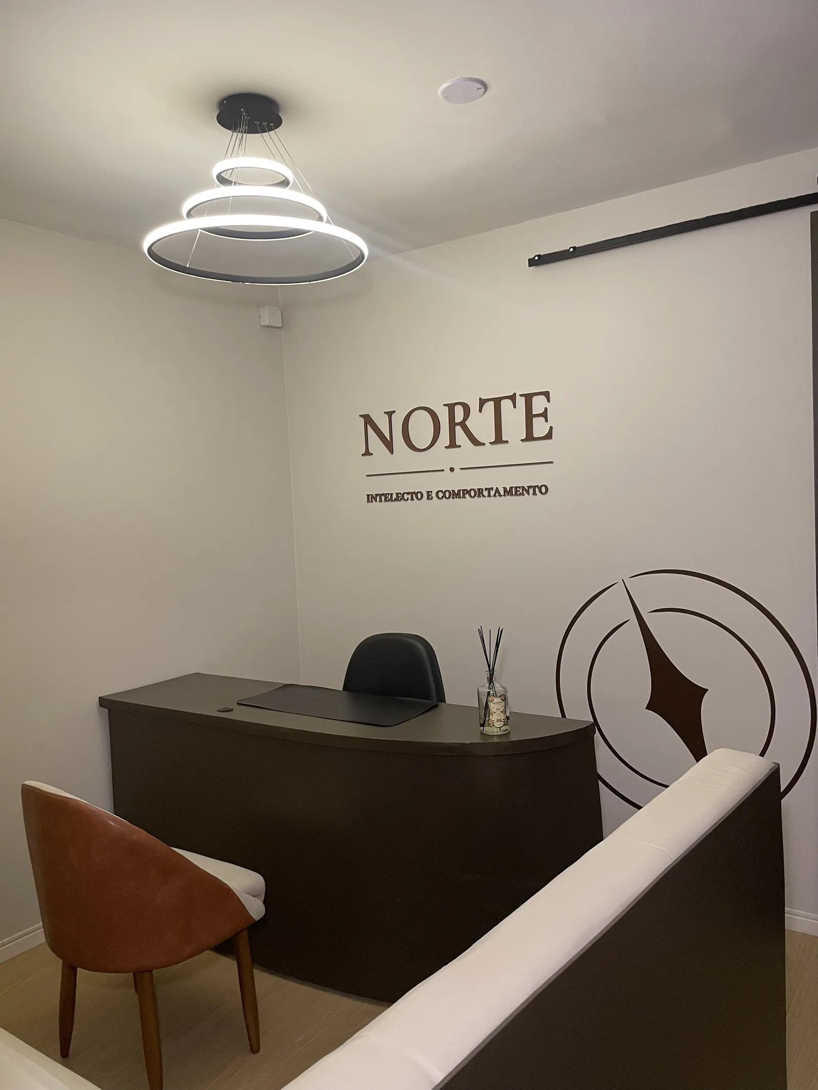 Espaço da NORTE com mesa de trabalho individual e identidade visual na parede